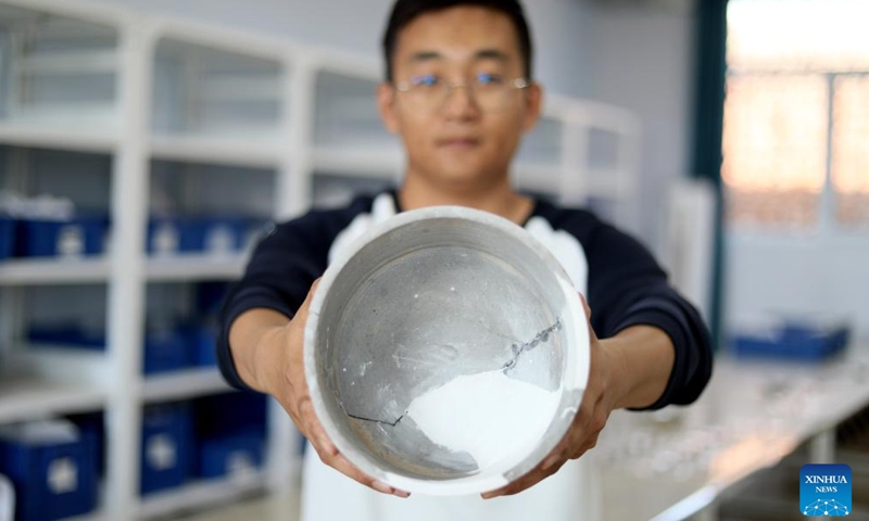 This photo taken on Oct. 25, 2023 shows an archaeologist from the Renmin University of China displaying a recovered pottery bowl unearthed at the Bairen Town site in the city of Xingtai, north China's Hebei Province.  (Photo: Xinhua)