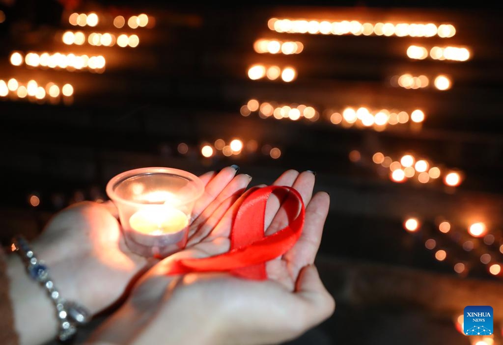 People hold a candle and a red ribbon during an event to raise awareness of AIDS at University of South China in Hengyang, central China's Hunan Province, Nov. 29, 2023. The World AIDS Day falls on Dec. 1.(Photo: Xinhua)