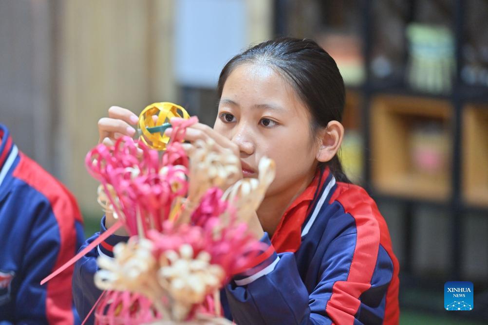 A student practices the bamboo weaving skill at Nandu primary school in Cenxi City, south China's Guangxi Zhuang Autonomous Region, Nov. 28, 2023. As a local intangible cultural heritage, the bamboo weaving skill was introduced to Nandu primary school in recent years, which enriched the extracurricular activities of the students.(Photo: Xinhua)
