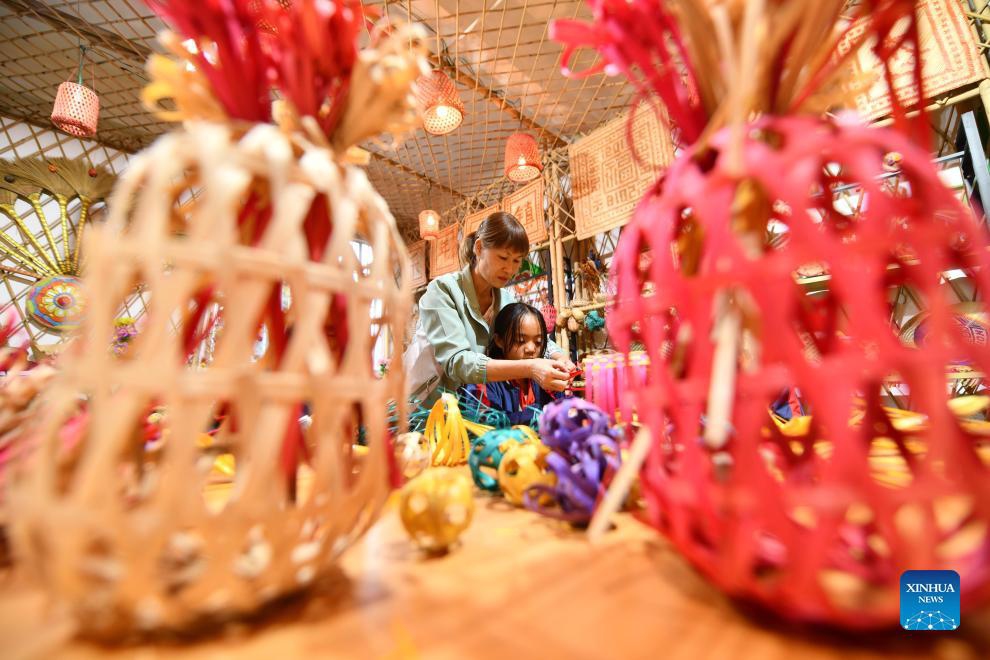 A student (R) learns the bamboo weaving skill from a teacher at Nandu primary school in Cenxi City, south China's Guangxi Zhuang Autonomous Region, Nov. 28, 2023. As a local intangible cultural heritage, the bamboo weaving skill was introduced to Nandu primary school in recent years, which enriched the extracurricular activities of the students.(Photo: Xinhua)