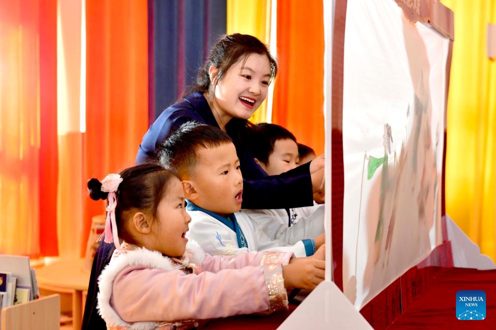 Teacher Zhu Qingmin teaches children to perform shadow play at Shanwang kindergarten in Jinan, east China's Shandong Province, Nov. 29, 2023. Shanwang kindergarten has set up many workshops for children to learn about traditional Chinese culture. Kids could receive various art education like shadow play, traditional Chinese painting and tie-dye techniques from teachers according to their interests.(Photo: Xinhua)