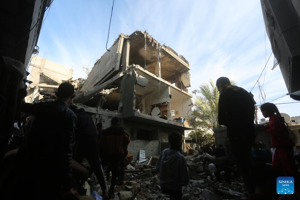 People are seen in front of a building destroyed in an Israeli strike in the southern Gaza Strip city of Rafah, on Dec. 7, 2023. Since Oct. 7, Israel has been launching a large-scale attack against Hamas in Gaza under the name Iron Swords, which has left 17,177 Palestinians dead, and more than 46,000 injured, said the Gaza-based Health Ministry on Thursday.(Photo: Xinhua)