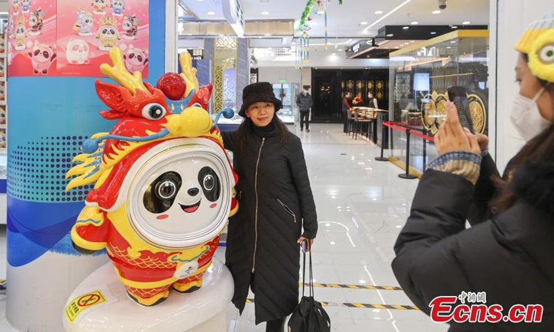 A woman poses for a photo with a Chinese zodiac Dragon version of Bing Dwen Dwen, a Beijing Winter Olympic Games mascot, at a store in Beijing, Dec. 7, 2023. (Photo: China News Service)
