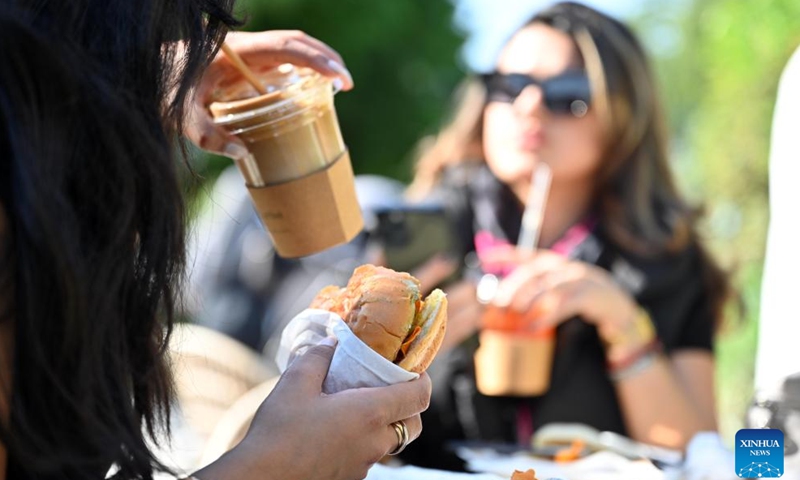 A woman enjoys food during the Qout Market Food Festival in Capital Governorate, Kuwait, Dec. 9, 2023. Nearly 100 local companies participated in the festival on Saturday. (Photo: Xinhua)
