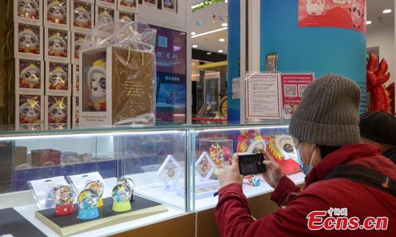 A customer takes photos of Chinese zodiac Dragon version of Bing Dwen Dwen, a Beijing Winter Olympic Games mascot, at a store in Beijing, Dec. 7, 2023. (Photo: China News Service)
