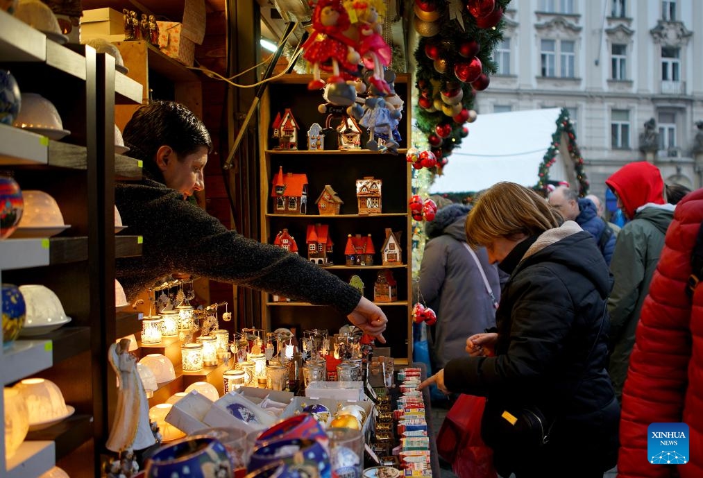 A woman selects holiday decorations at a Christmas market in Prague, the Czech Republic, on Dec. 12, 2023.(Photo: Xinhua)