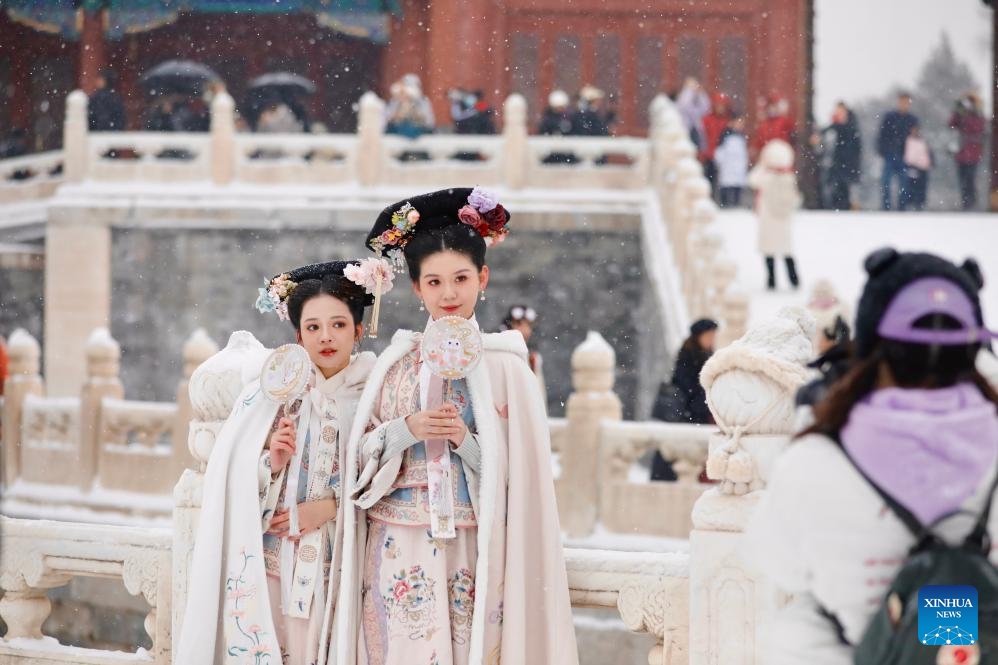 Tourists pose for photos in snow at the Palace Museum in Beijing, capital of China, Dec. 13, 2023. China's meteorological authority on Wednesday renewed a yellow alert for blizzards, forecasting intense snowfall in the north of the country.(Photo: Xinhua)