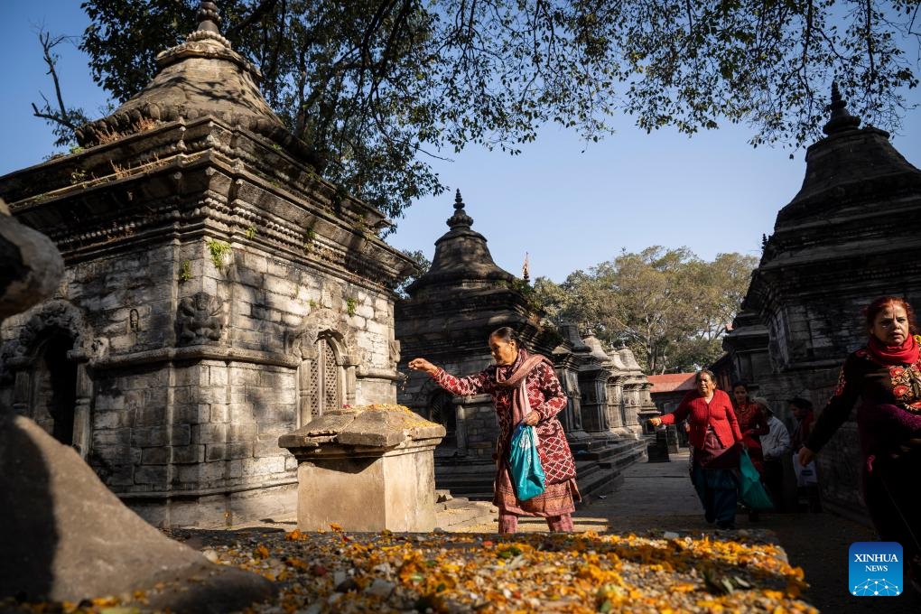 A woman scatters a mixture of seven types of grains as a tradition to observe the Bala Chaturdashi Festival in Kathmandu, Nepal, Dec. 11, 2023.(Photo: Xinhua)