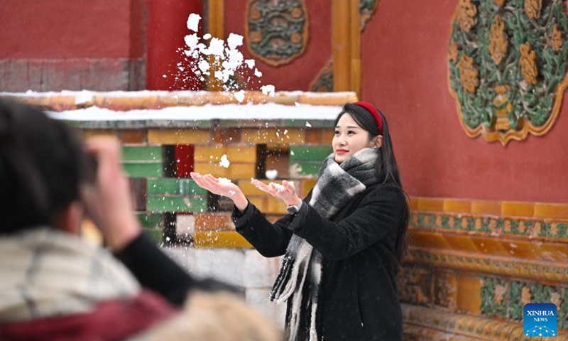 A tourist poses for a photo in snow at the Palace Museum in Beijing, capital of China, Dec. 13, 2023. China's meteorological authority on Wednesday renewed a yellow alert for blizzards, forecasting intense snowfall in the north of the country.(Photo: Xinhua)