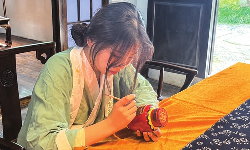 The yellow rice wine inheritor is decorating a wine bottle. Photo: Li Hang/GT