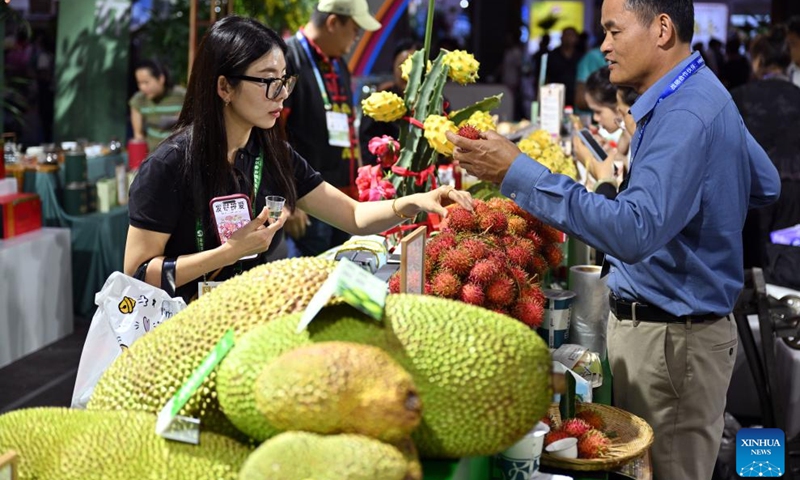 Visitors select tropical fruits from Qiongzhong City during the 26th China (Hainan) International Tropical Agricultural Products Winter Trade Fair in Haikou, south China's Hainan Province, Dec. 14, 2023. Covering an area of around 80,000 square meters, the 26th China (Hainan) International Tropical Agricultural Products Winter Trade Fair kicked off here on Thursday. Exhibits of the four-day event will focus on fruits and vegetables, grain and oil, aquatic products, and cross-border e-commerce. (Photo: Xinhua)