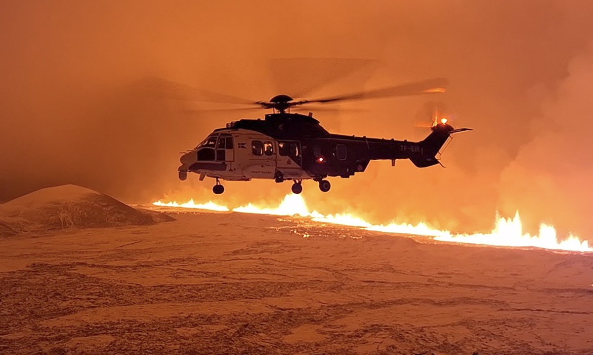 An Icelandic Coast Guard helicopter overflies a volcanic eruption on the Reykjanes Peninsula 3 kilometers north of Grindavik, western Iceland on December 19, 2023. Experts say they do not expect it will bring the same level of disruption as the eruption in Iceland in 2010, which halted European air travel. Photo: AFP