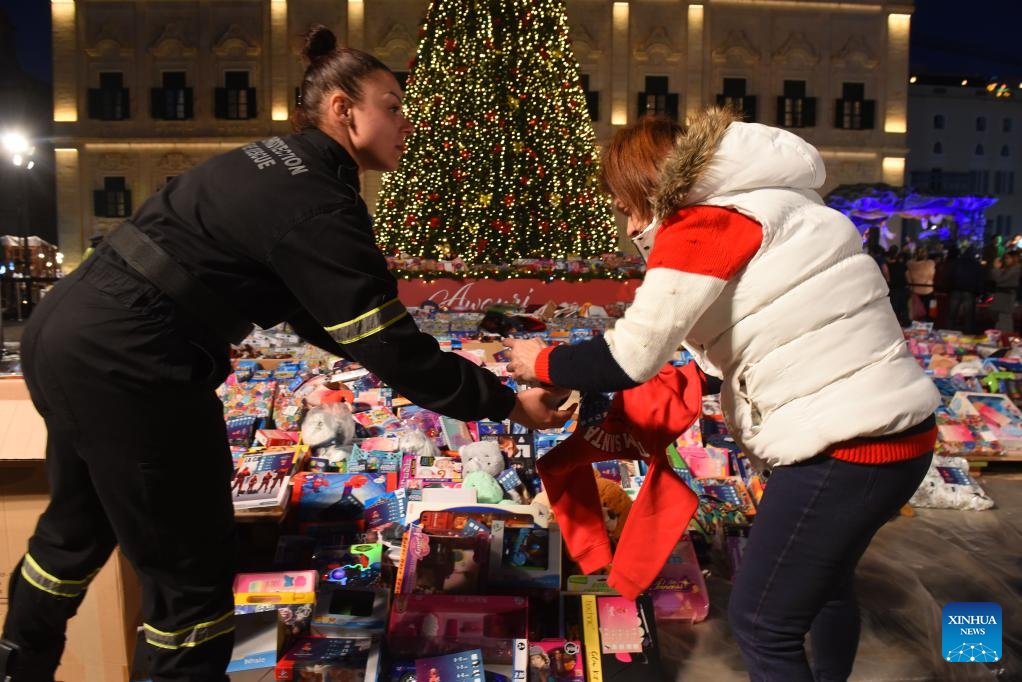 A woman (R) donates a Christmas gift at Castille Square in Valletta, Malta, on Dec. 21, 2023. A charitable event of donating Christmas gifts for children in need is held here on Thursday.(Photo: Xinhua)