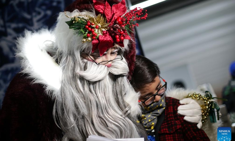 A man dressed in Santa Claus costume hugs a child at a subway station in Mexico City, Mexico on Dec. 19, 2023.(Photo: Xinhua)