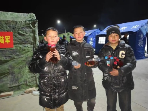 Children help out by handing out drinks to parched rescuers on December 20, 2023. Photo: People's Daily