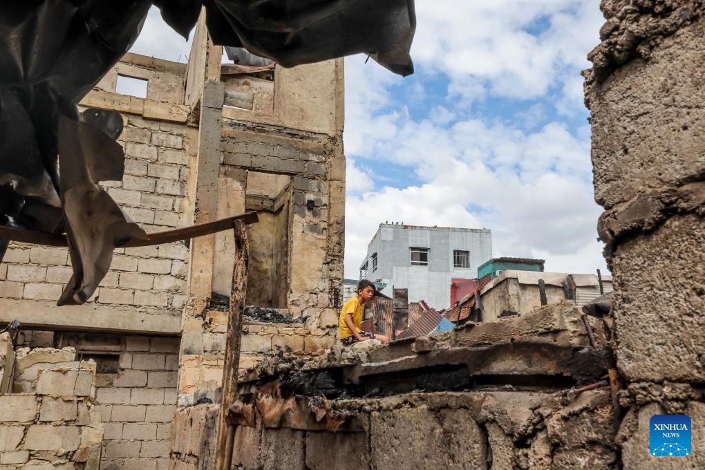 A resident is seen as he returns to the charred houses after a fire at a slum area in Manila, the Philippines, on Dec. 20, 2023.(Photo: Xinhua)