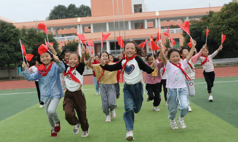 Students take a photo holding national flags at Qingshuiping School in Baojing county, Hunan Province on September 27, 2023. Photo: VCG