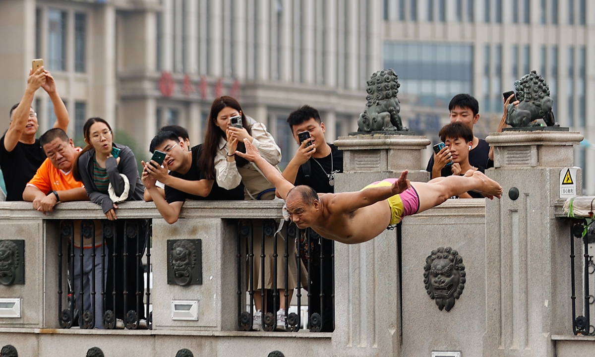 Tourists take photos as a Tianjin grandpa dives into the Haihe River. Photo: VCG