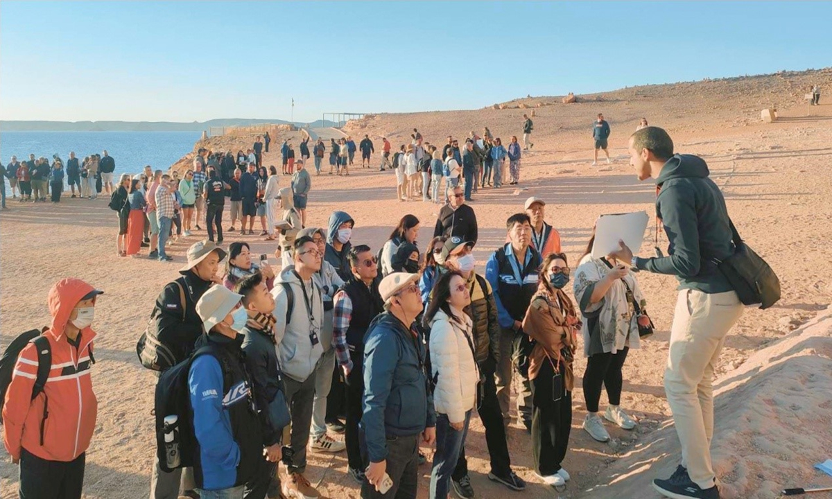 Abbas El-Said introduces an Egyptian attraction to Chinese tourists. The photo was published on page 18 of the People's Daily newspaper issued on Dec. 25, 2023. (Photo: People's Daily)