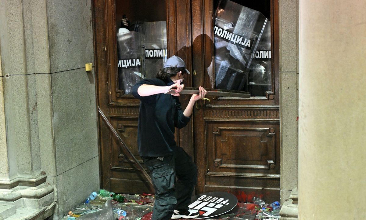 A protester uses a metal object against police officers guarding the entrance to Belgrade's city council building during a demonstration in Belgrade, Serbia, on December 24, 2023. Photo: AFP