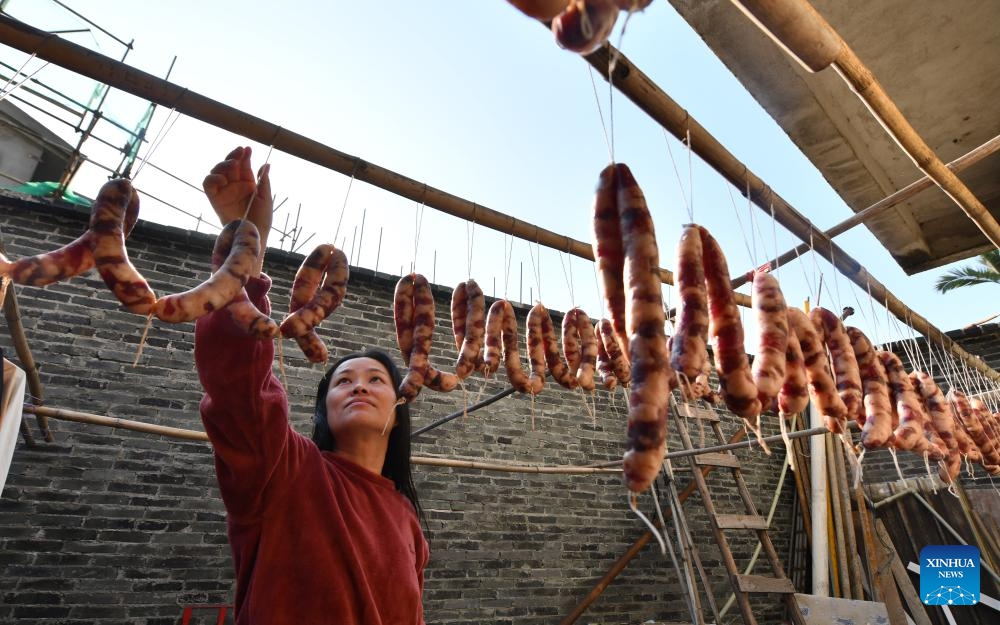 A villager dries sausages in Zhongdu Town of Luzhai County, south China's Guangxi Zhuang Autonomous Region, Dec. 26, 2023. The alluring aroma of cured meat has wafted out as winter comes.(Photo: Xinhua)