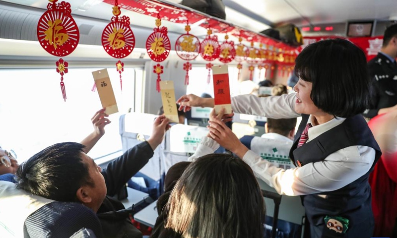 A staff member interacts with passengers with blessing cards on the train G980 from Shenyang to Beijing, in northeast China's Liaoning Province, Jan. 1, 2024. Monday marks the last day of the three-day 2024 New Year holiday in China.Photo:Xinhua