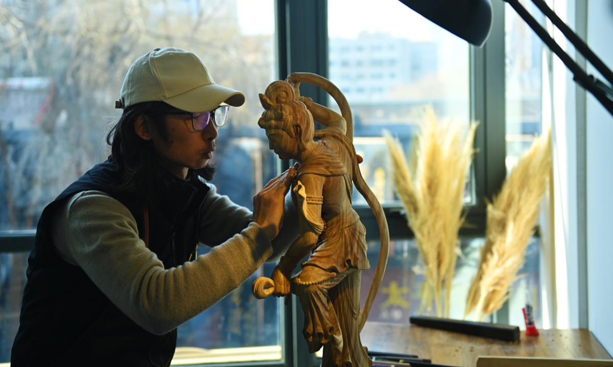 Ji Maojie, a 45-year-old woodcarving artist, creates a sculpture inspired by the murals of the Mogao Grottoes in Dunhuang, a UNESCO World Heritage Site, in Lanzhou, Northwest China's Gansu Province on January 3, 2024. Ji has been using a carving knife to tranform the flat images in the Dunhuang murals and transformed them into vivid 3D sculptures. Photo: VCG