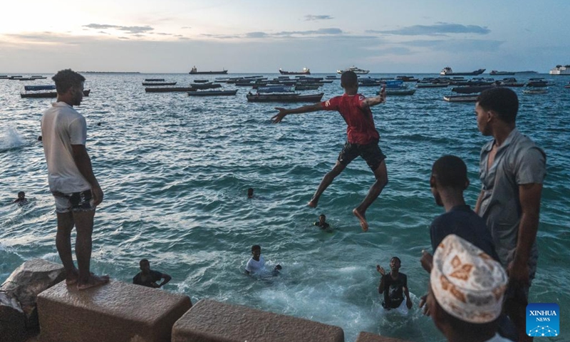 People entertain themselves at seaside in Zanzibar, Tanzania, Dec. 31, 2023. Zanzibar consists of two large coral islands - Zanzibar and Pemba, and more than 20 adjacent islets. For nearly 10 centuries, Zanzibar has blended the diverse cultures of Africa, Asia and Europe, becoming an important cultural attraction and holiday destination in East Africa. (Photo: Xinhua)