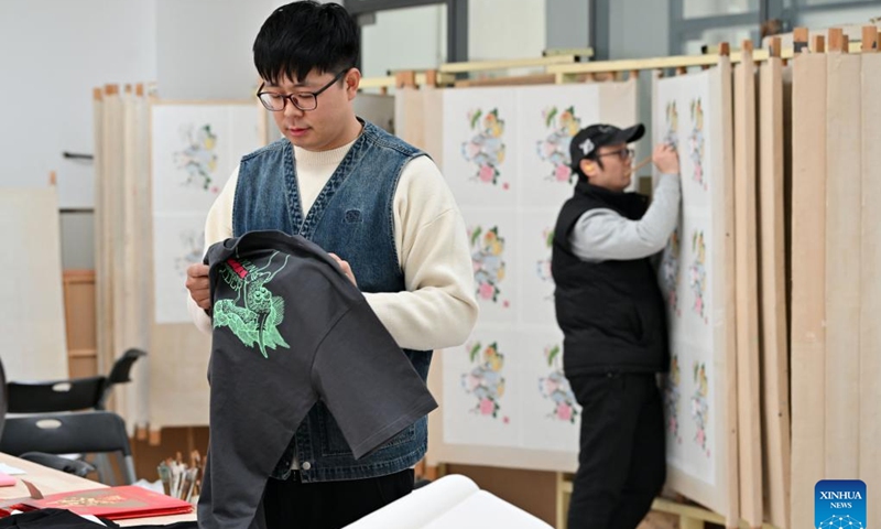 Xi Wang checks a T-shirt bearing elements of traditional new year pictures at the Tianjin Yangliuqing picture studio in Tianjin, north China, Dec. 26, 2023. (Photo: Xinhua)