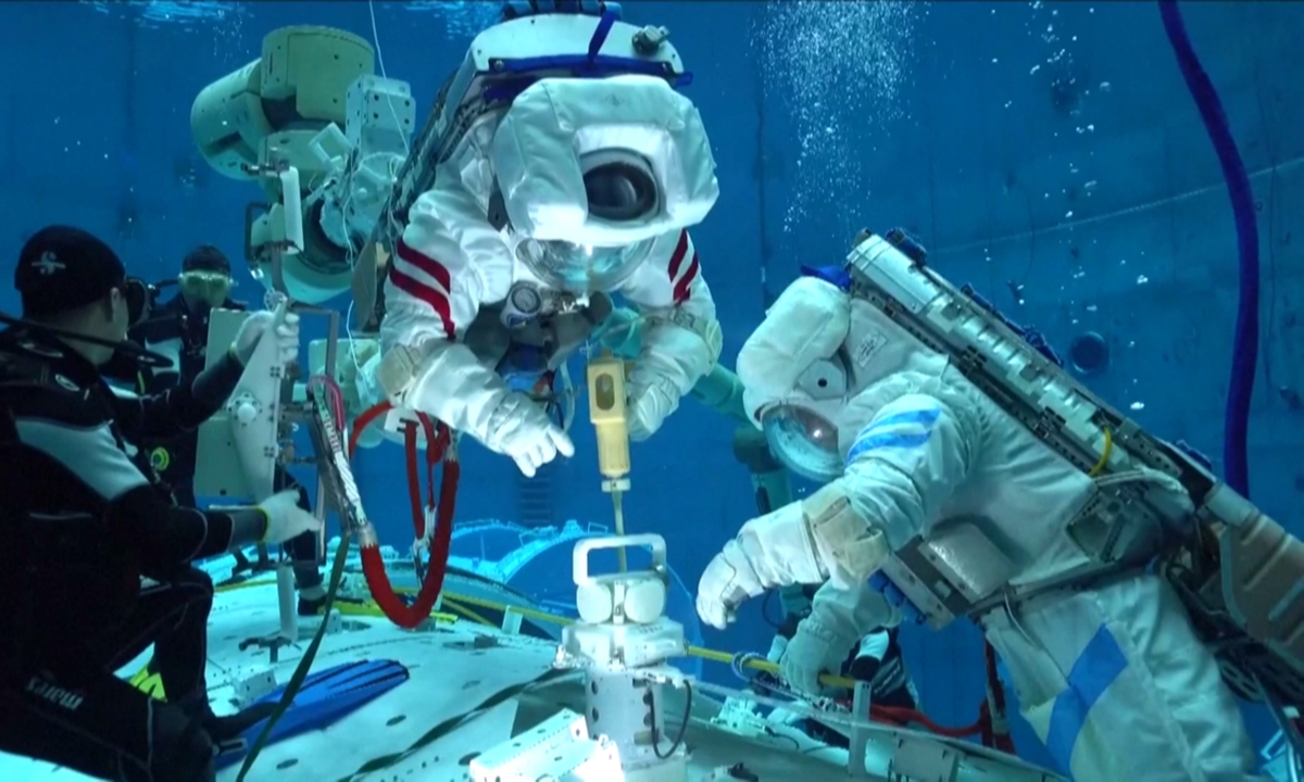 The Shenzhou 16 astronaut crew simulates opening the hatch door and wearing space suits underwater during the training in May 2023. Photo: VCG 
