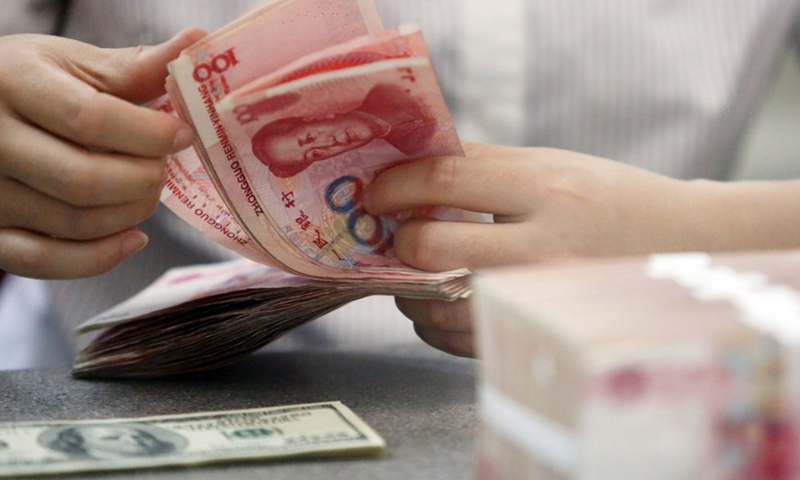 File photo shows a worker counts Chinese currency Renminbi (RMB) at a bank in Linyi, east China's Shandong Province. (Xinhua/Zhang Chunlei)