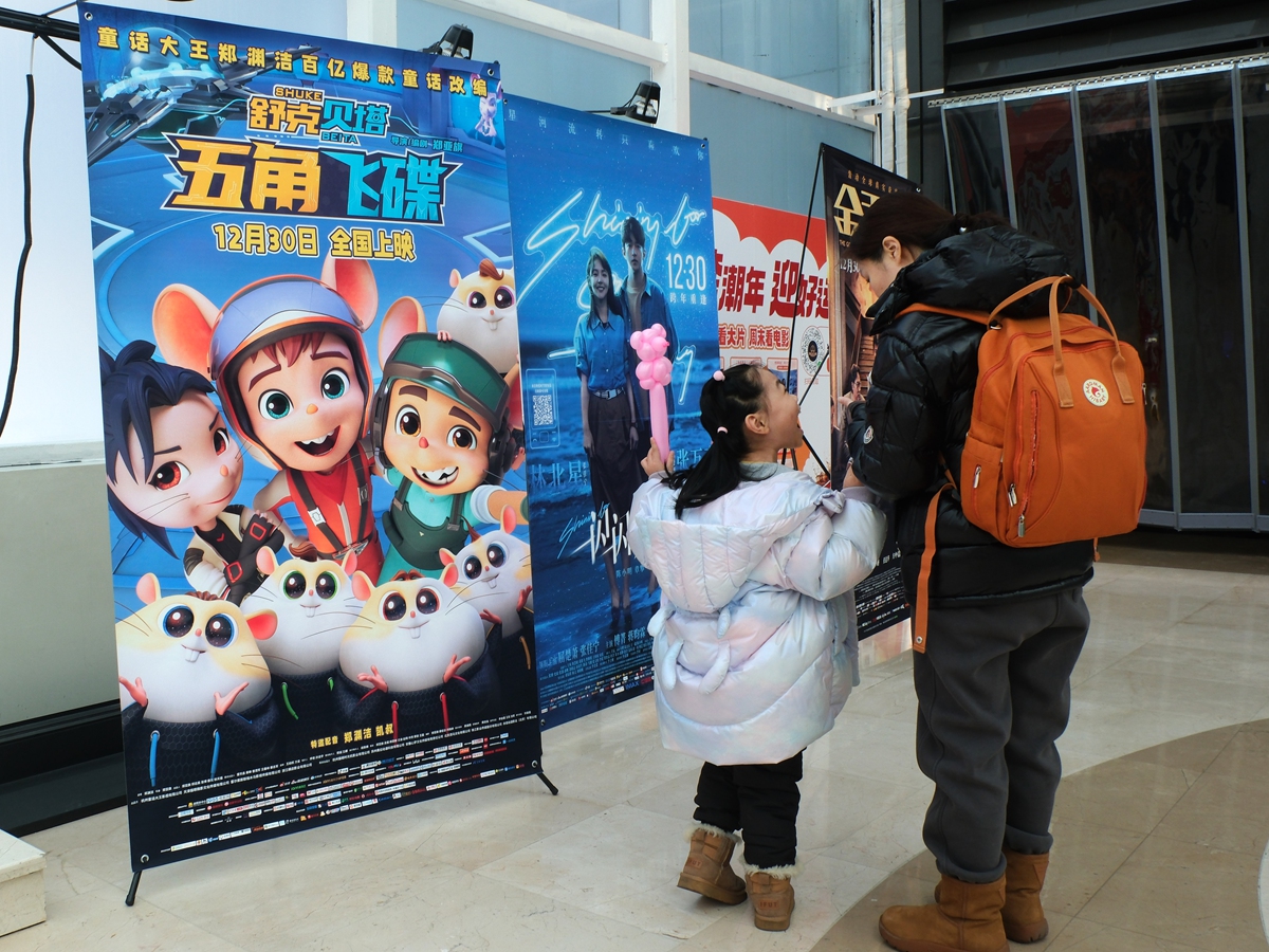 A girl and an adult stand before movie posters in a cinema during the New Year's Day holidays in Shenyang, Northeast China's Liaoning Province. Photo: VCG