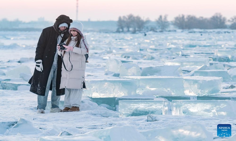 Tourists take photos at an ice amusement spot on the Songhuajiang River Harbin section in Harbin, northeast China's Heilongjiang Province, Jan. 7, 2024. Dubbed China's ice city, Harbin has recently seen a tourism boom. An ice amusement spot, transformed from an ice collecting site out of use, has attracted lots of visitors to have fun here with ice packs scattered on the Songhuajiang River Harbin section. (Xinhua/Xie Jianfei)