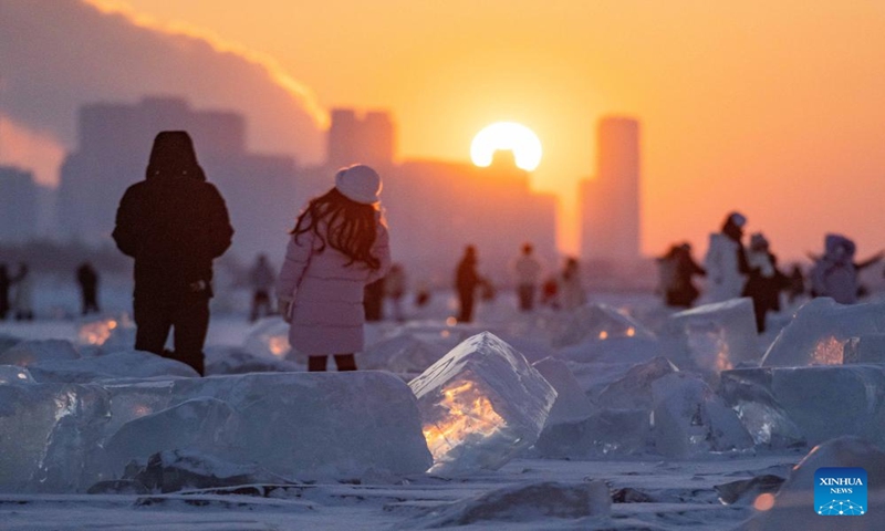Tourists are seen at an ice amusement spot in sunset on the Songhuajiang River Harbin section in Harbin, northeast China's Heilongjiang Province, Jan. 7, 2024. Dubbed China's ice city, Harbin has recently seen a tourism boom. An ice amusement spot, transformed from an ice collecting site out of use, has attracted lots of visitors to have fun here with ice packs scattered on the Songhuajiang River Harbin section. (Xinhua/Xie Jianfei)