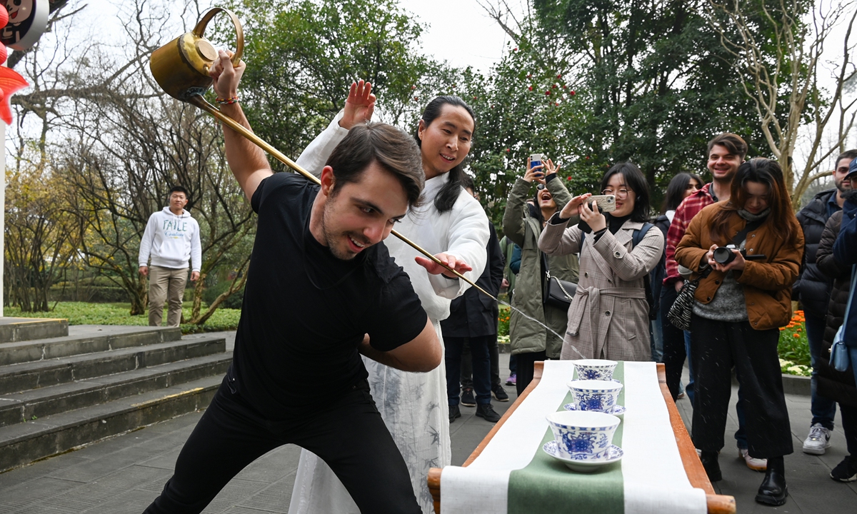 A foreigner takes part in a long-spout teapot pouring performance in Chengdu, Southwest China's Sichuan Province, on January 8, 2024. With a history of more than 1,000 years and combining tea art and Chinese kung fu, long-spout teapot pouring is one of the main tourist attractions in Sichuan. Photo: VCG