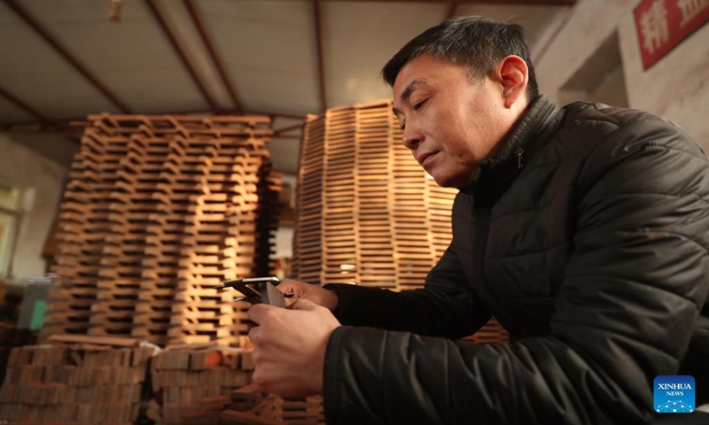 Gong Zhiguang measures a block for erhu making in Changtu County of Tieling City, northeast China's Liaoning Province, Dec. 28, 2023. (Xinhua/Yang Qing)