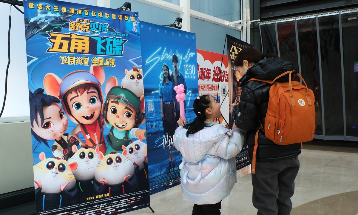 A girl and an adult stand before movie posters in a cinema during the New Year's Day holidays in Shenyang, Northeast China's Liaoning Province. Photo: VCG