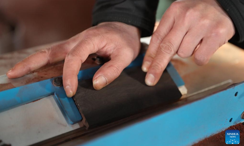 Gong Zhiguang cuts a block for erhu making in Changtu County of Tieling City, northeast China's Liaoning Province, Dec. 28, 2023.
