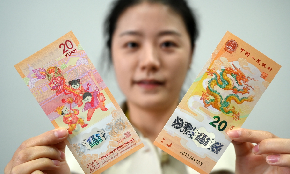 A woman displays her Chinese New Year 2024 banknotes in Neijiang, Southwest China's Sichuan Province, on January 9, 2024. The Year of the Dragon will fall on February 10. From January 9 to 15, people who have made an appointment can go to designated bank branches on an agreed upon date with their ID cards to purchase Chinese New Year 2024 commemorative notes. Photo: VCG