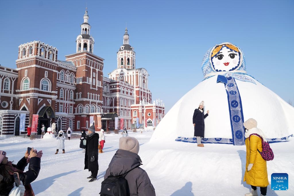 People pose for photos in front of a giant snowman at the Volga Manor in Harbin, northeast China's Heilongjiang Province, Jan. 7, 2024. The Volga Manor, a Russian culture-themed park, turned into a world of ice and snow during the winter time, attracting lots of visitors.(Photo: Xinhua)