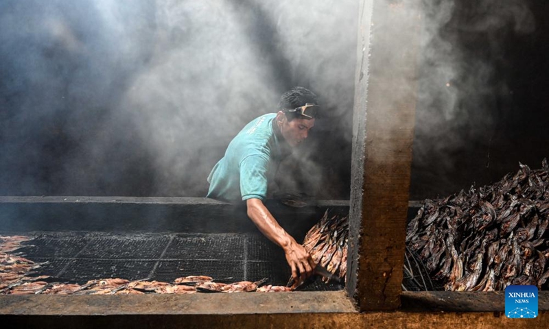 A worker collects smoked catfish slices from a grill at a traditional workshop in Bogor, West Java, Indonesia, on Jan. 10, 2024. This traditional workshop in Bogor produces up to 500 kilograms of smoked catfish slices daily for domestic consumption as well as export to Malaysia and Nigeria.(Photo: Xinhua)