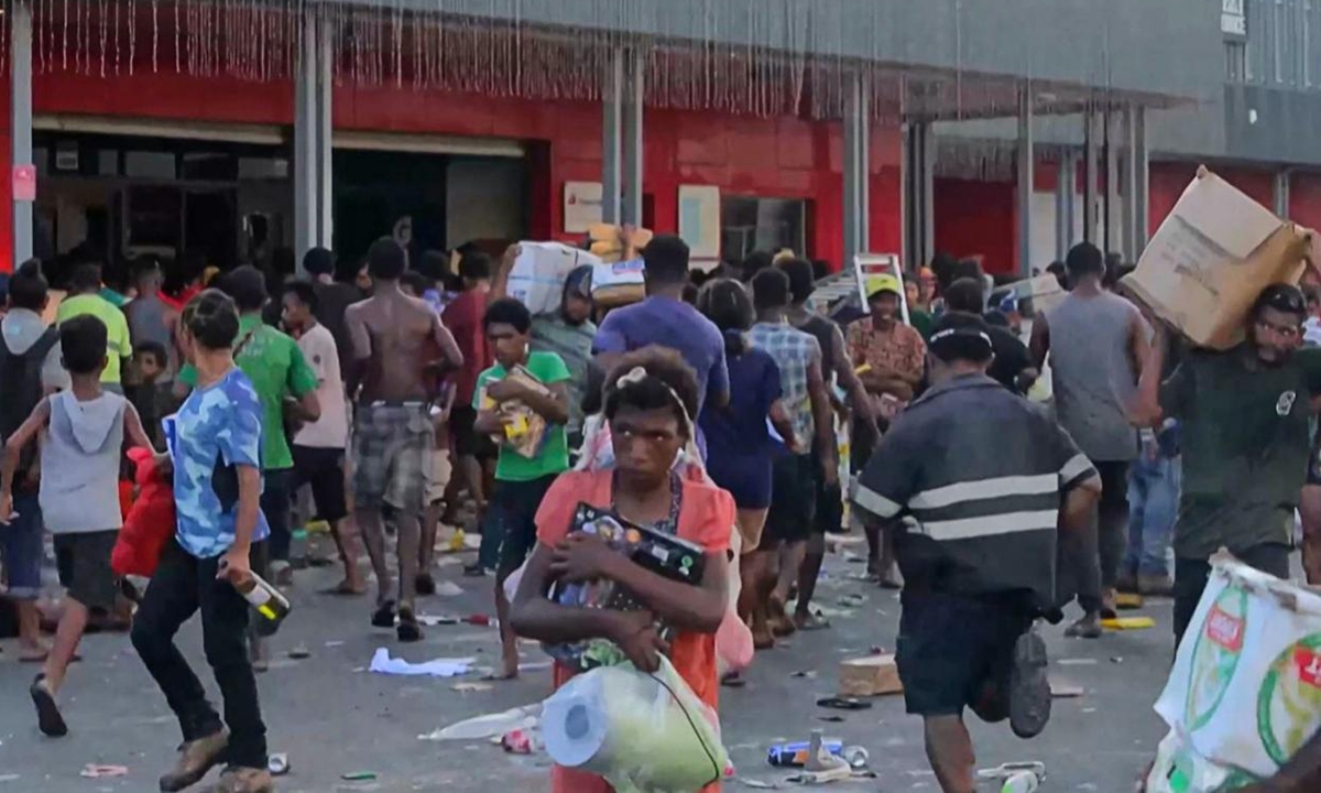 This screen grab from AFPTV video footage taken on January 10, 2024 shows people carrying items as crowds leave shops with looted goods amid a state of unrest in Port Moresby. Photo: VCG