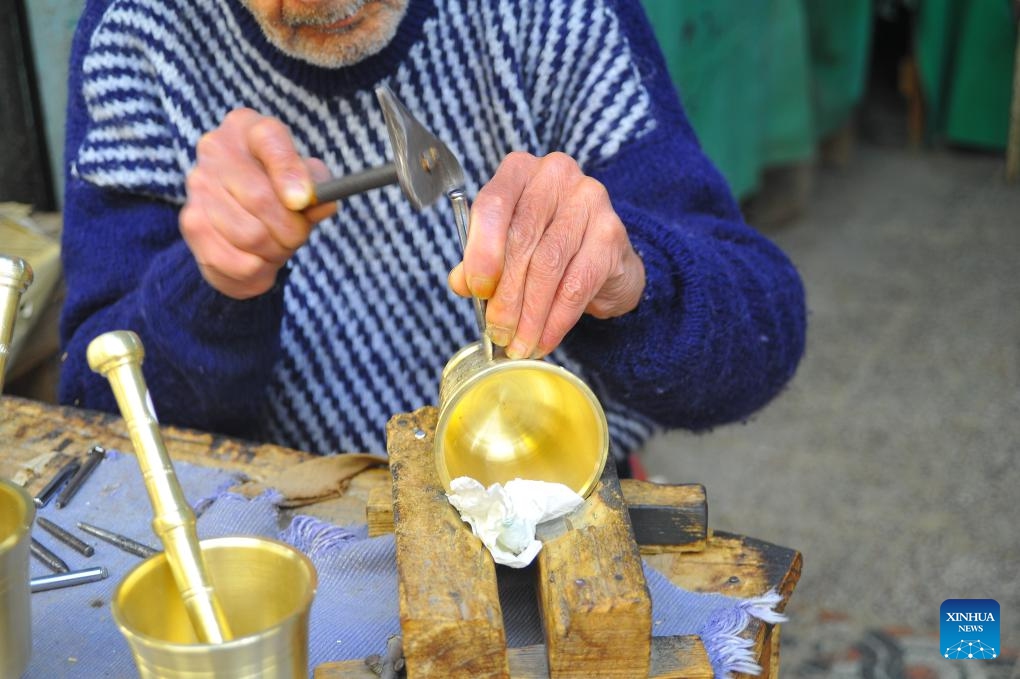 A craftsman carves patterns on a metalware in the Medina of Tunis, Tunisia on Jan. 9, 2024. Engraved metal objects are the main tourist souvenirs in Tunisia. The arts, skills and practices associated with engraving on metals, such as gold, silver and copper, which are widely spread in Arab countries, were inscribed in 2023 on the Representative List of the Intangible Cultural Heritage of Humanity.(Photo: Xinhua)