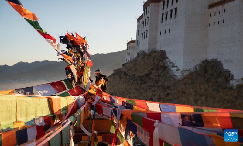 A man hangs prayer flags in Sangzhuzi District in Xigaze, southwest China's Xizang Autonomous Region, Jan. 14, 2024.