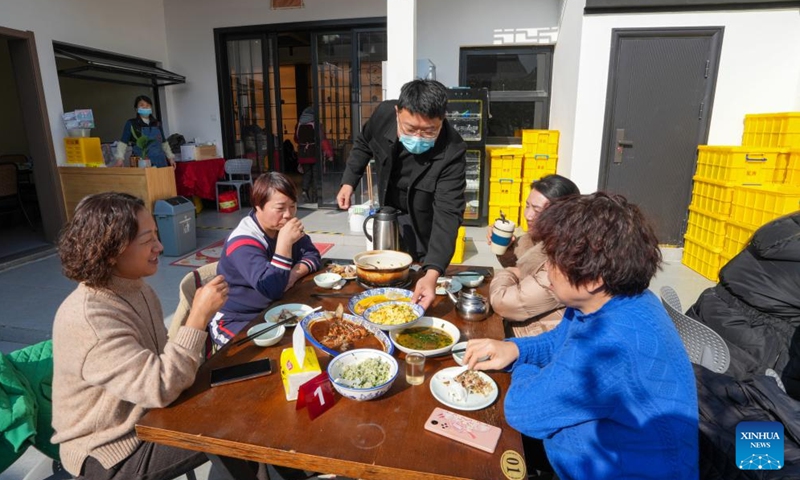 Liu Yuelong (3rd L), an agritainment owner, serves the table in Shushan Village in Tong'an Town of Suzhou City, east China's Jiangsu Province, Jan. 11, 2024.