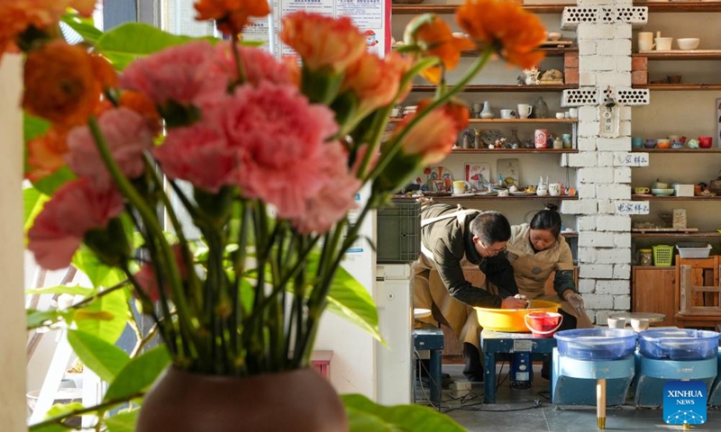 Wang Guangliang (L), an art studio owner, teaches pottery craft to a tourist in Shushan Village in Tong'an Town of Suzhou City, east China's Jiangsu Province, Jan. 11, 2024.
