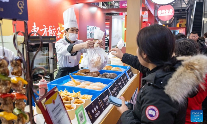Tourists buy food during a food festival in Harbin, northeast China's Heilongjiang Province, Jan. 20, 2024. (Xinhua/Xie Jianfei)