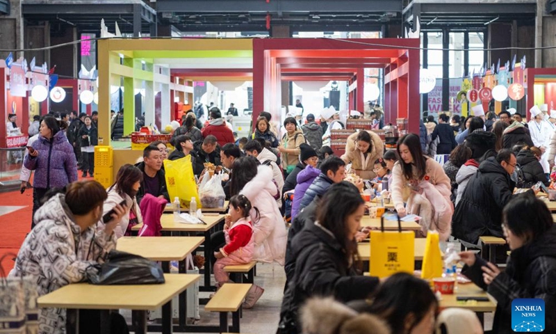 Tourists taste food during a food festival in Harbin, northeast China's Heilongjiang Province, Jan. 20, 2024. (Xinhua/Xie Jianfei)