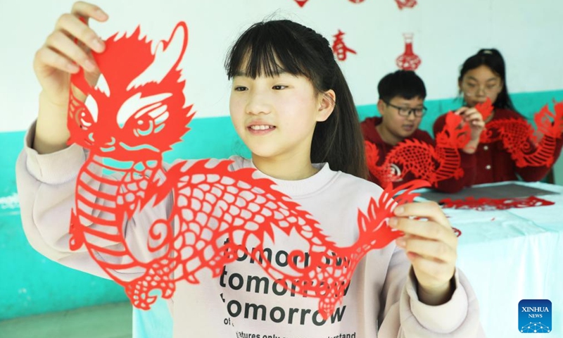 A student shows a paper cutting work in the shape of a dragon in Tangshan, north China's Hebei Province, Jan. 12, 2024. China's 2024 Spring Festival holiday will run from Feb. 10 to 17. (Photo by Zhu Dayong/Xinhua)