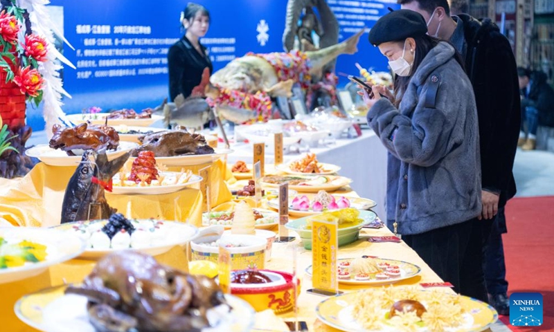 A tourist takes photos of various dishes during a food festival in Harbin, northeast China's Heilongjiang Province, Jan. 20, 2024. (Xinhua/Xie Jianfei)